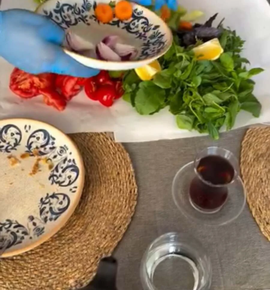 Fresh greens, tomatoes, radishes and lemon being arranged on the table