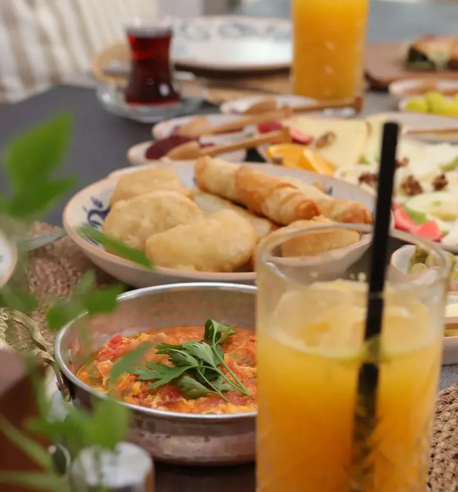 A copper sahan of menemen beside fresh orange juice and Turkish tea
