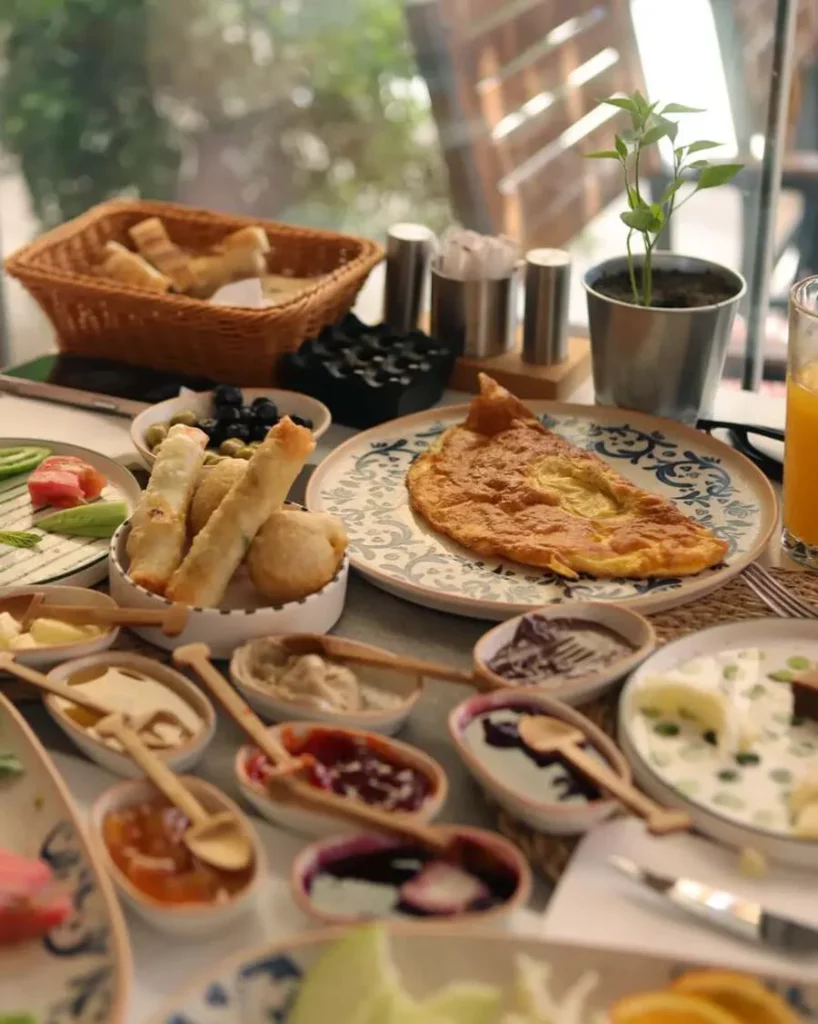 A full Turkish breakfast spread: omelette, börek, jams in small bowls with wooden spoons